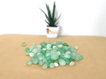 Green stones on a beige surface with a plant in the background