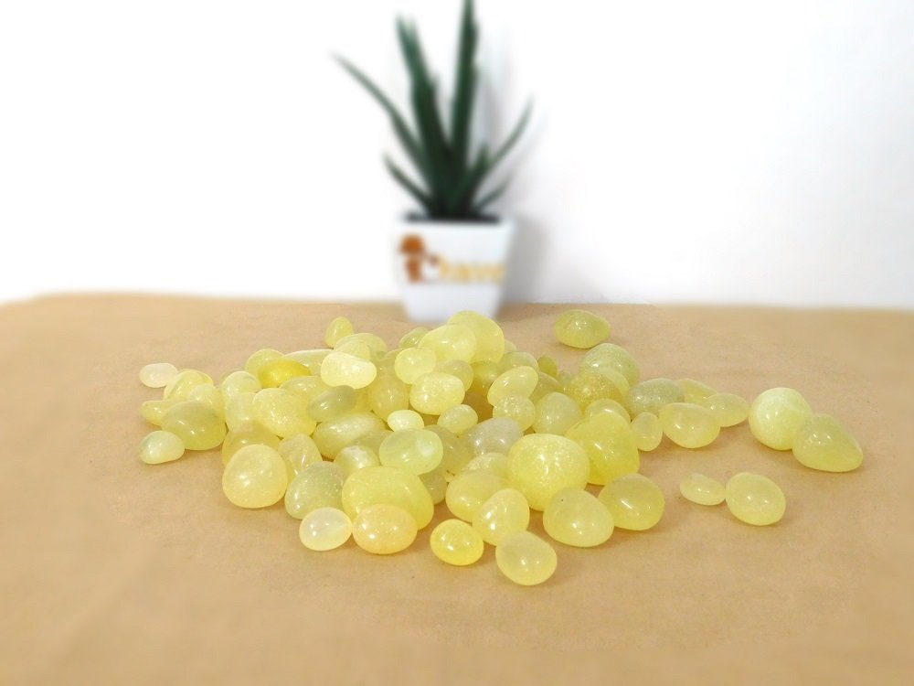 Yellow beads on a beige surface with a blurred plant in the background