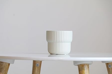 White textured pot on a white shelf with wooden legs against a light gray background