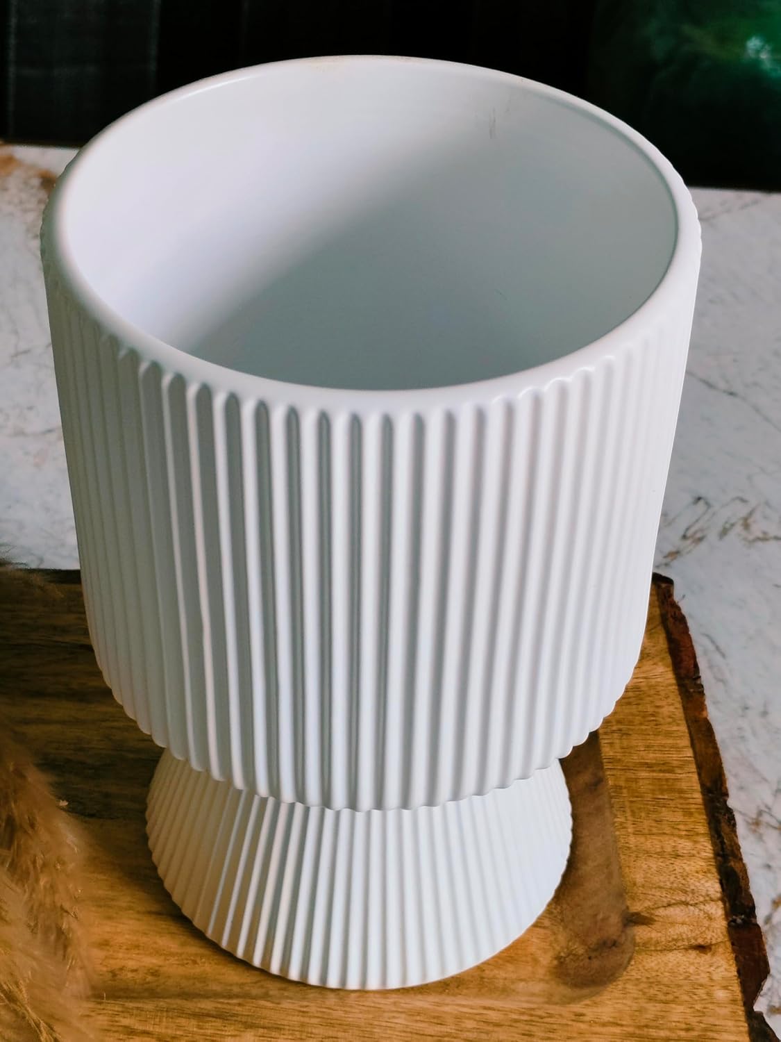 White textured vase on a wooden surface with a blurred background