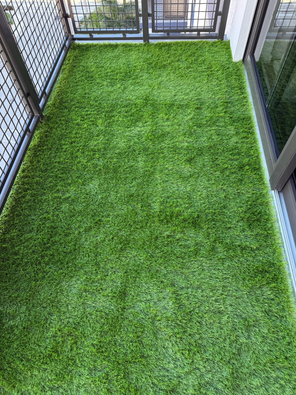 Artificial grass on a balcony with a metal railing.