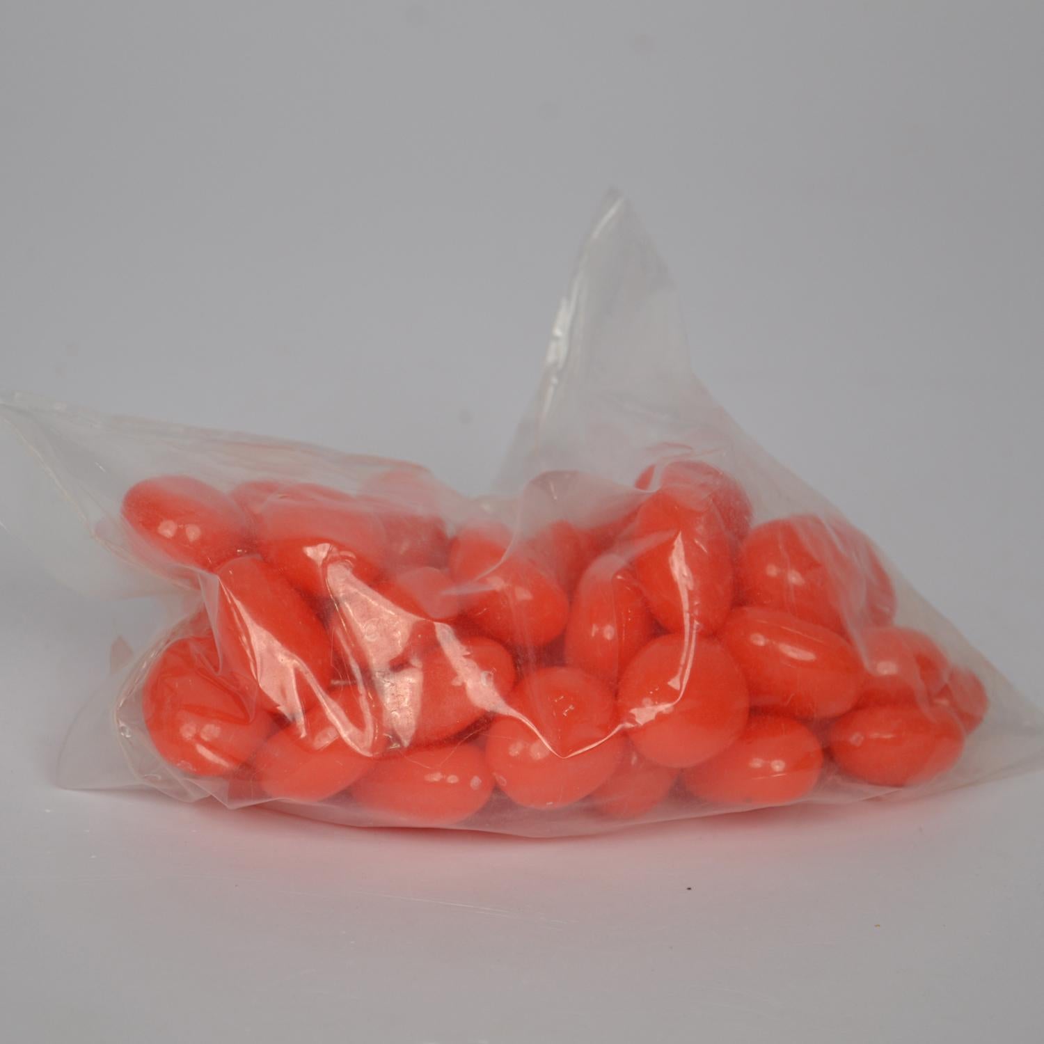 Clear bag filled with orange pebbles on a white background