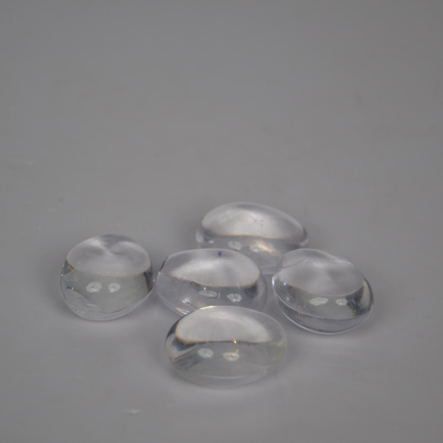 Five clear glass stones on a gray background