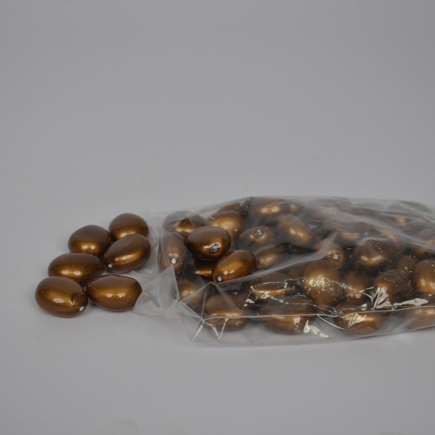 Gold pebbles spilling out of a clear plastic bag on a gray background