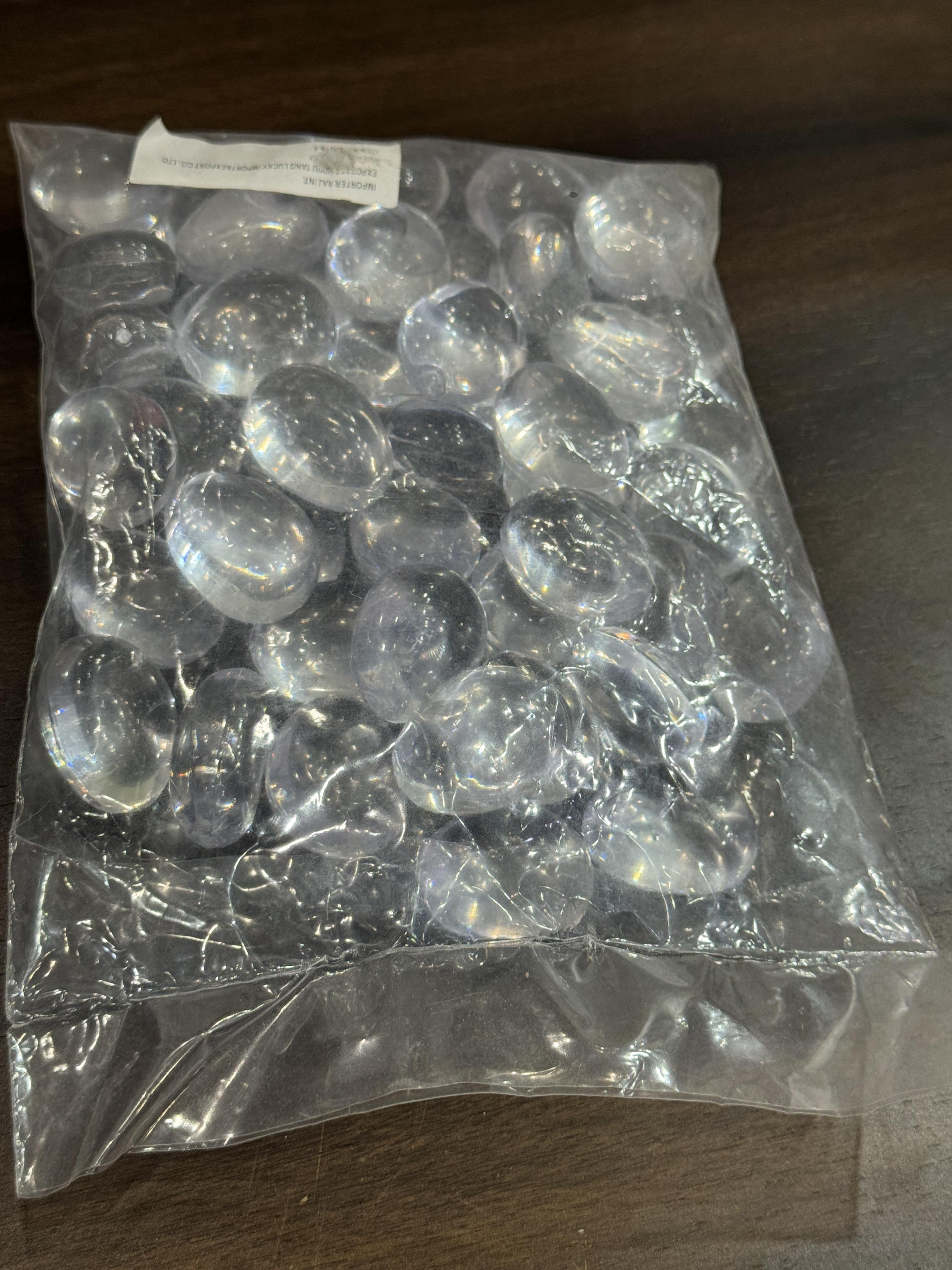Clear plastic pebbles in a transparent bag on a wooden surface