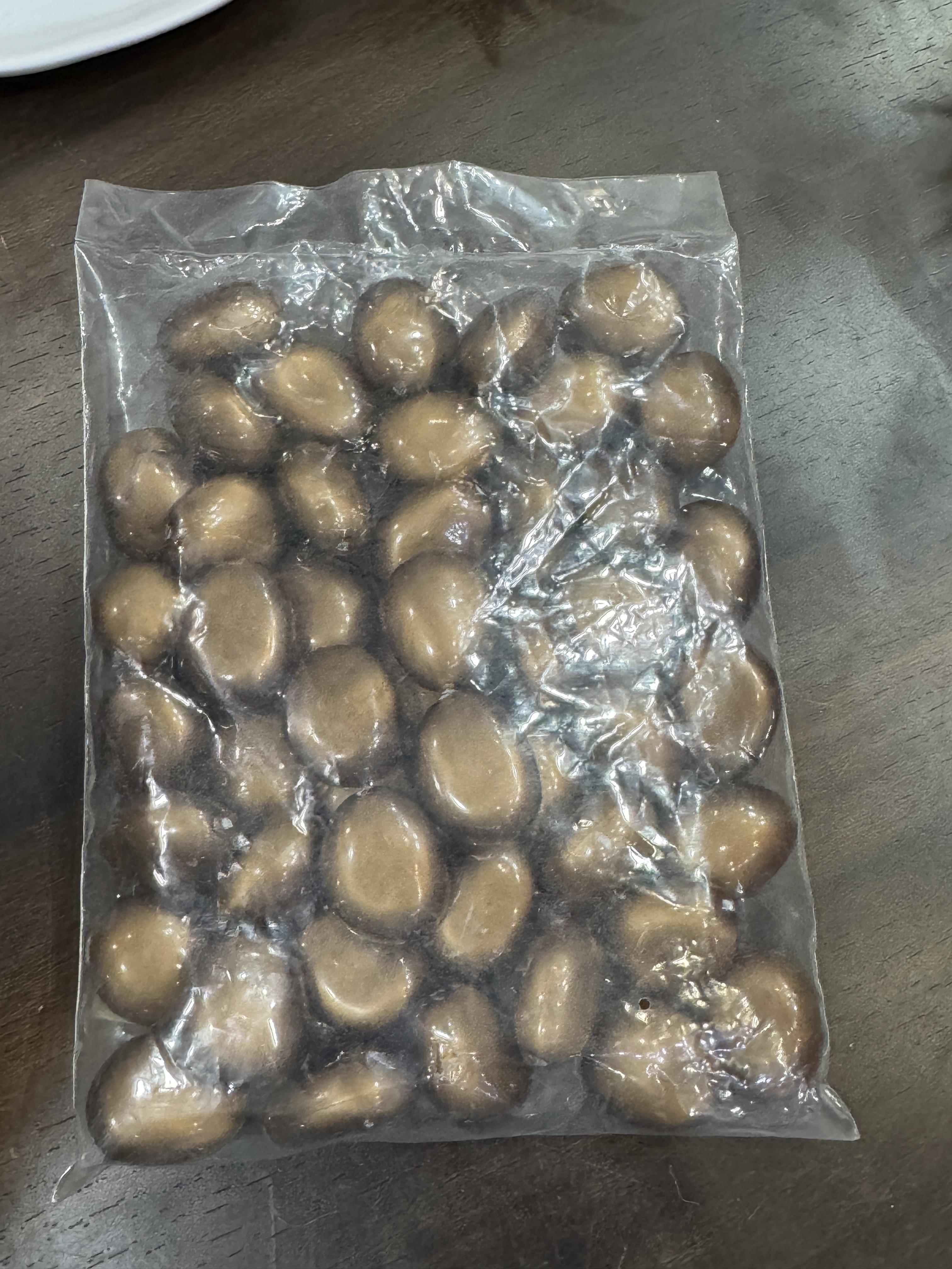 Clear plastic bag filled with brown stones on a wooden surface
