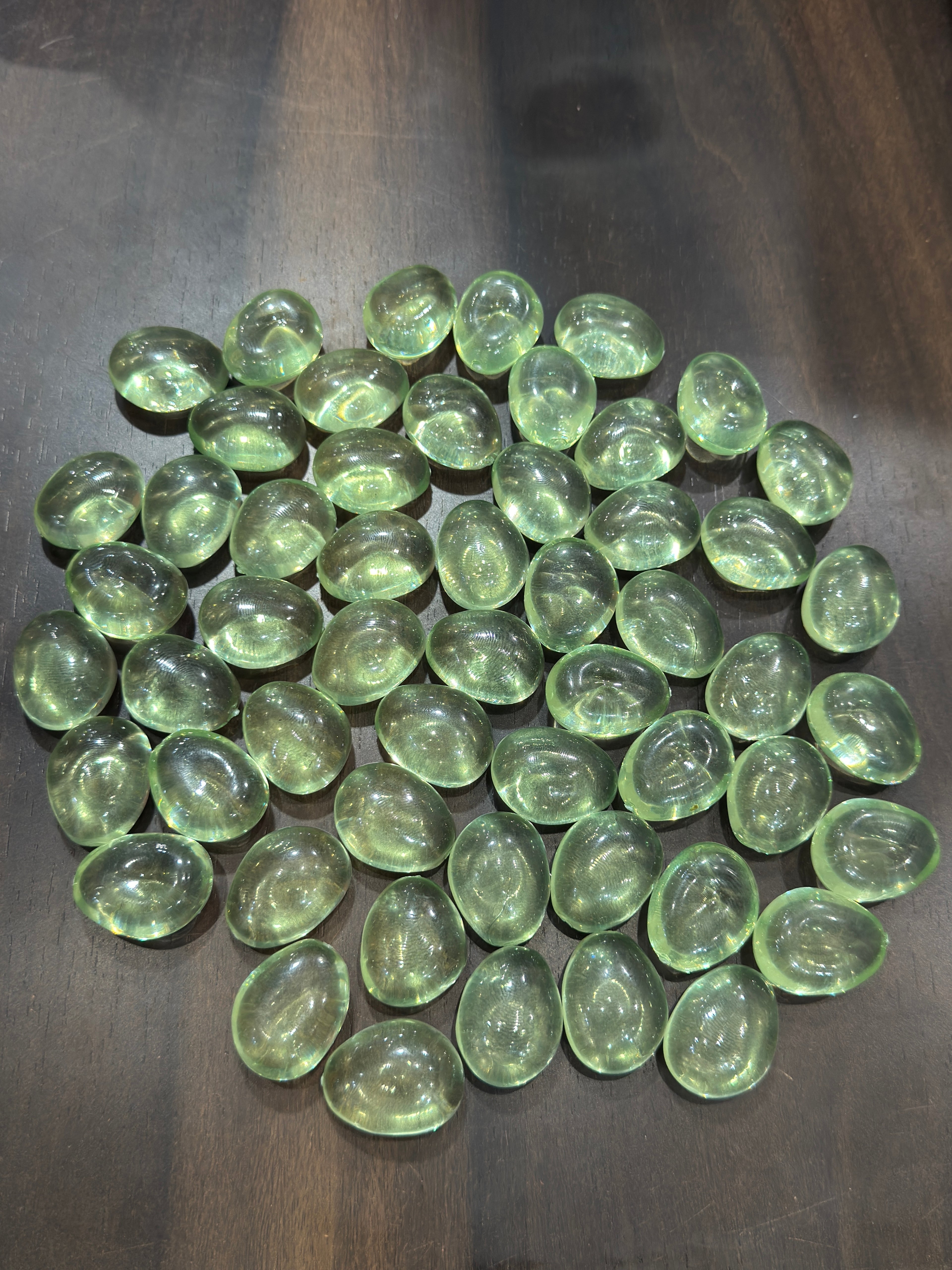 Green glass marbles on a dark wooden surface