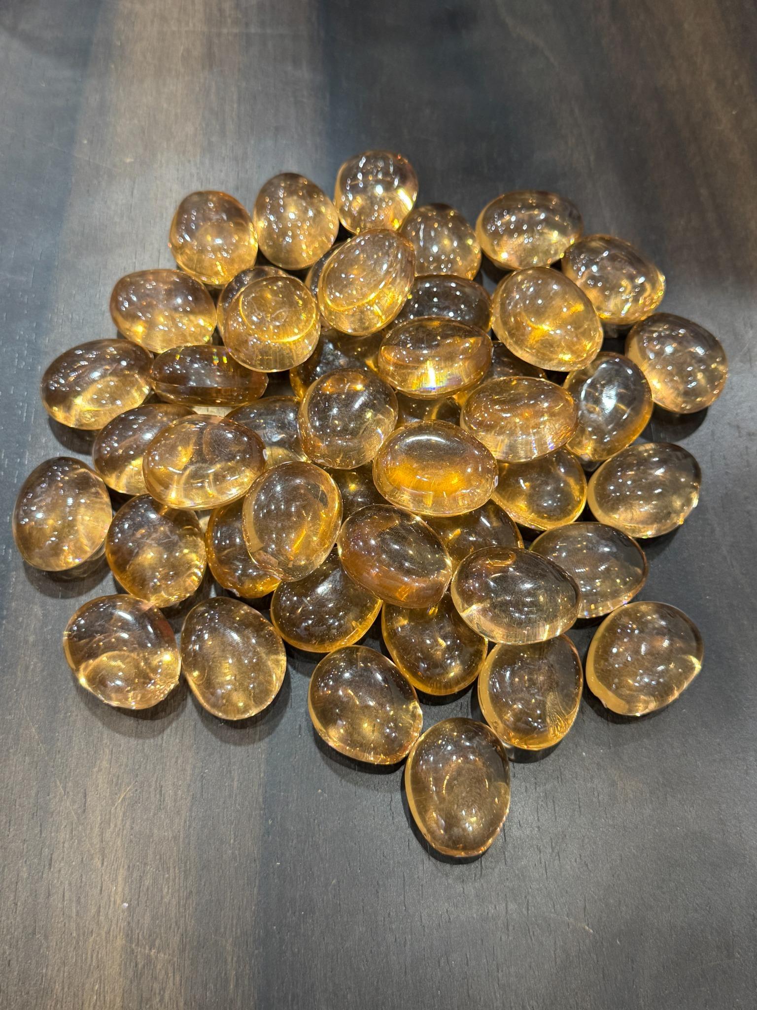 Collection of transparent amber-colored glass marbles on a dark surface