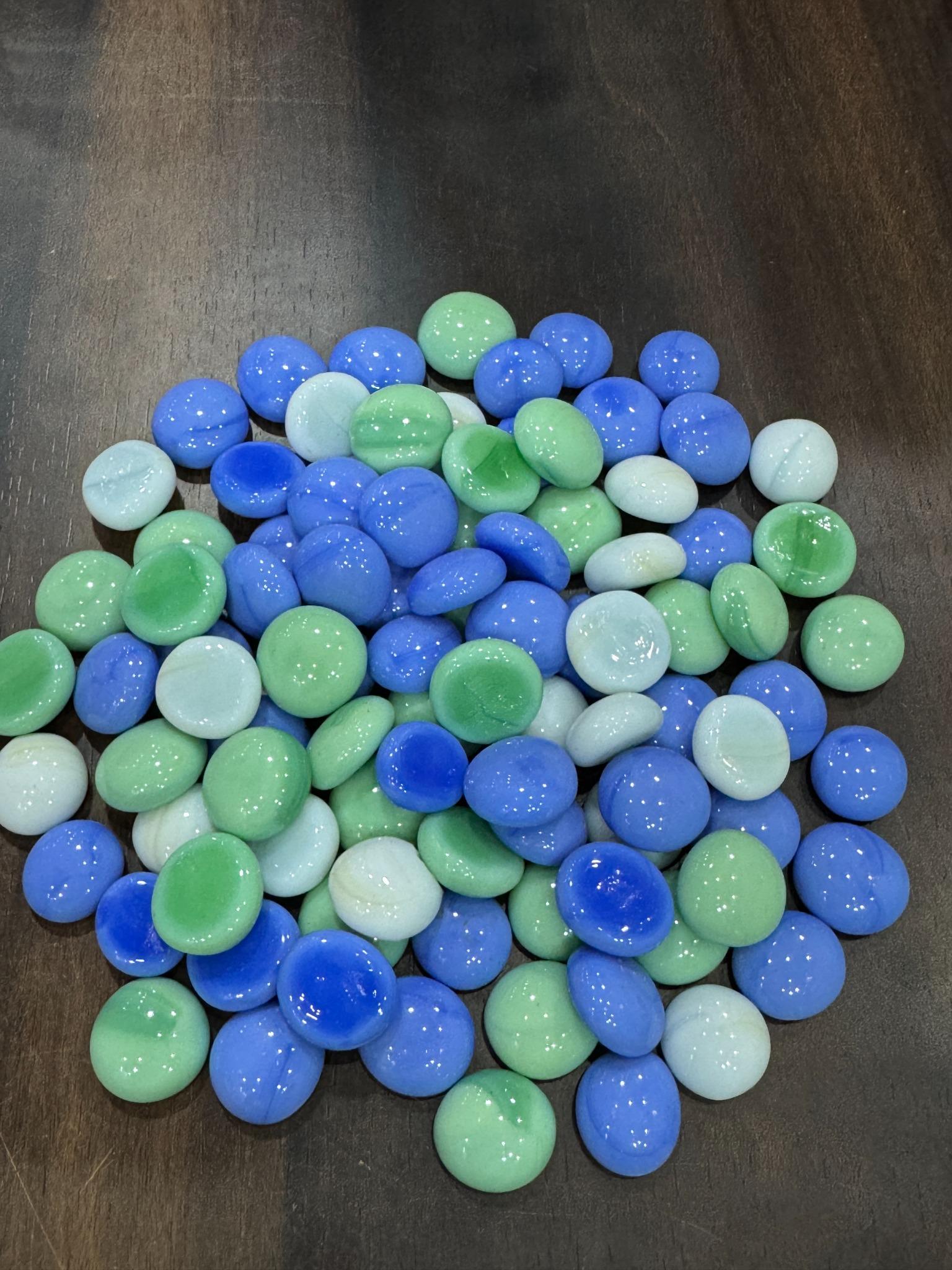 Blue and green marbles on a dark surface