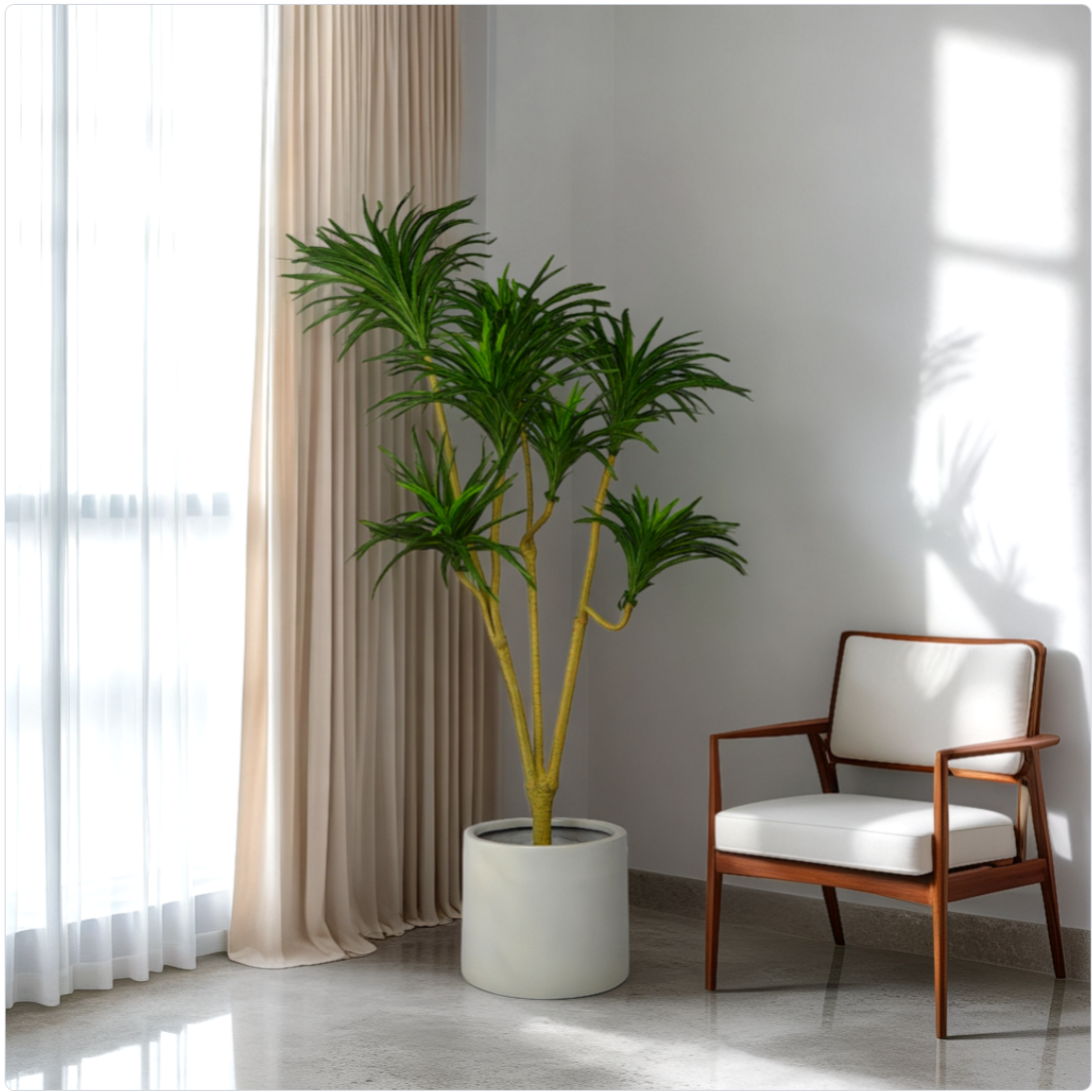 A 5 ft artificial Dracaena plant in a white pot placed in a home interior setting, next to a window with curtains and a chair.