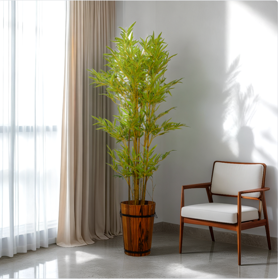 A 5 ft artificial bamboo plant in a brown pot, placed in a room corner beside a window with curtains and a chair.