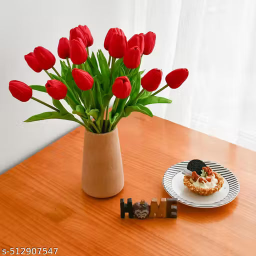 Bouquet of red tulips in a beige vase on a wooden table with a dessert and chocolate bars.
