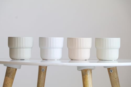 Four white ceramic pots on a white surface with wooden legs against a light gray background