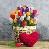 Basket of colorful tulips with a red heart on a wooden surface and gray background