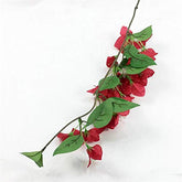 Artificial red bougainvillea flower branch with green leaves on a white background