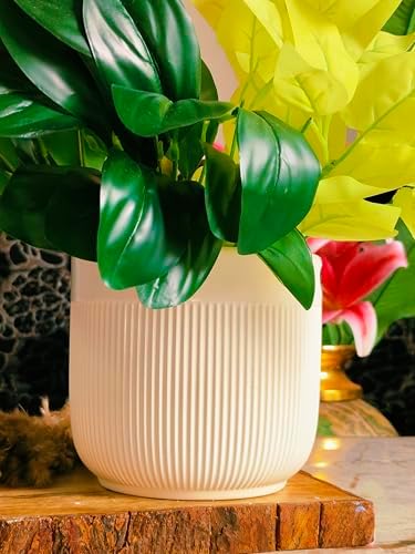 White textured vase with green leaves on a wooden surface