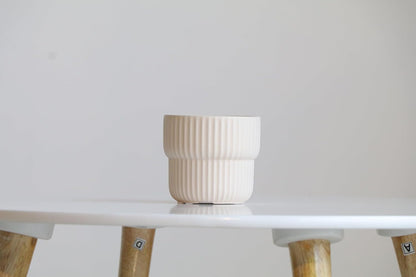 White ceramic pot on a white surface with a light gray background