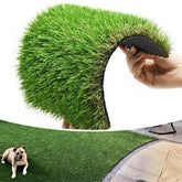 Hand holding a roll of artificial grass with a dog lying on a installed patch.