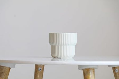 White textured pot on a white shelf with wooden legs against a light gray background