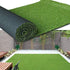 Roll of artificial grass with a garden setting in the background