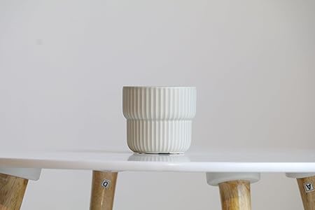 White ceramic pot on a white table with wooden legs against a light gray background
