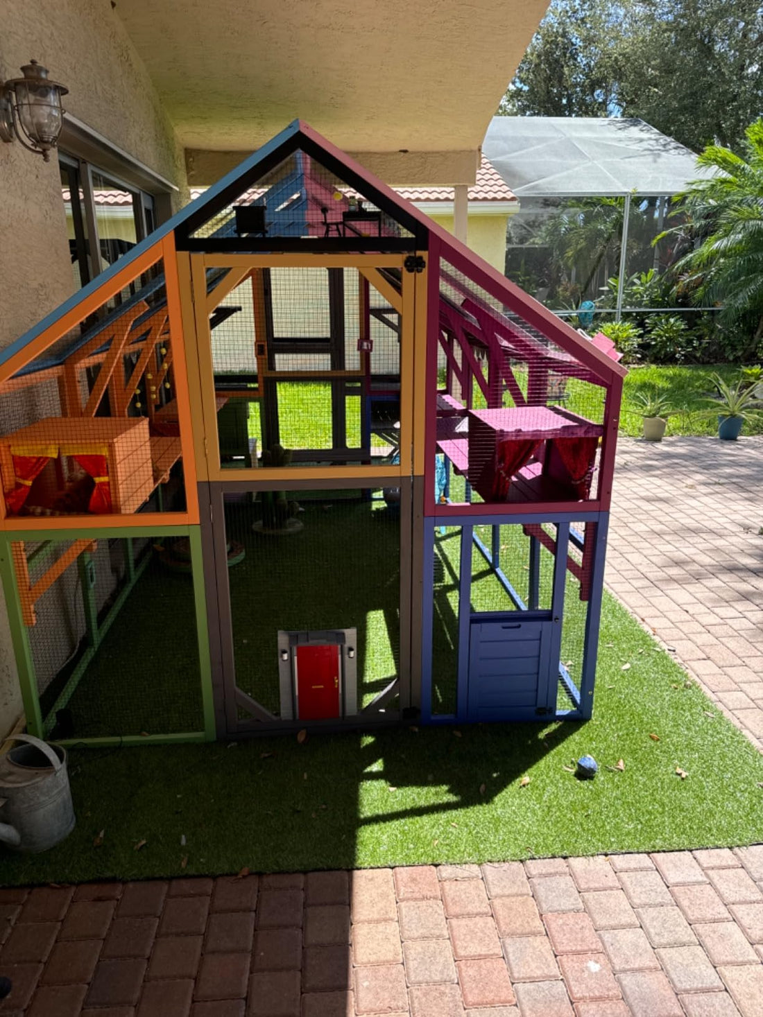 Colorful playhouse on a patio with grass and a house in the background