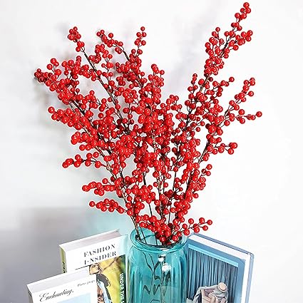 Red berry branches in a blue vase on a white background