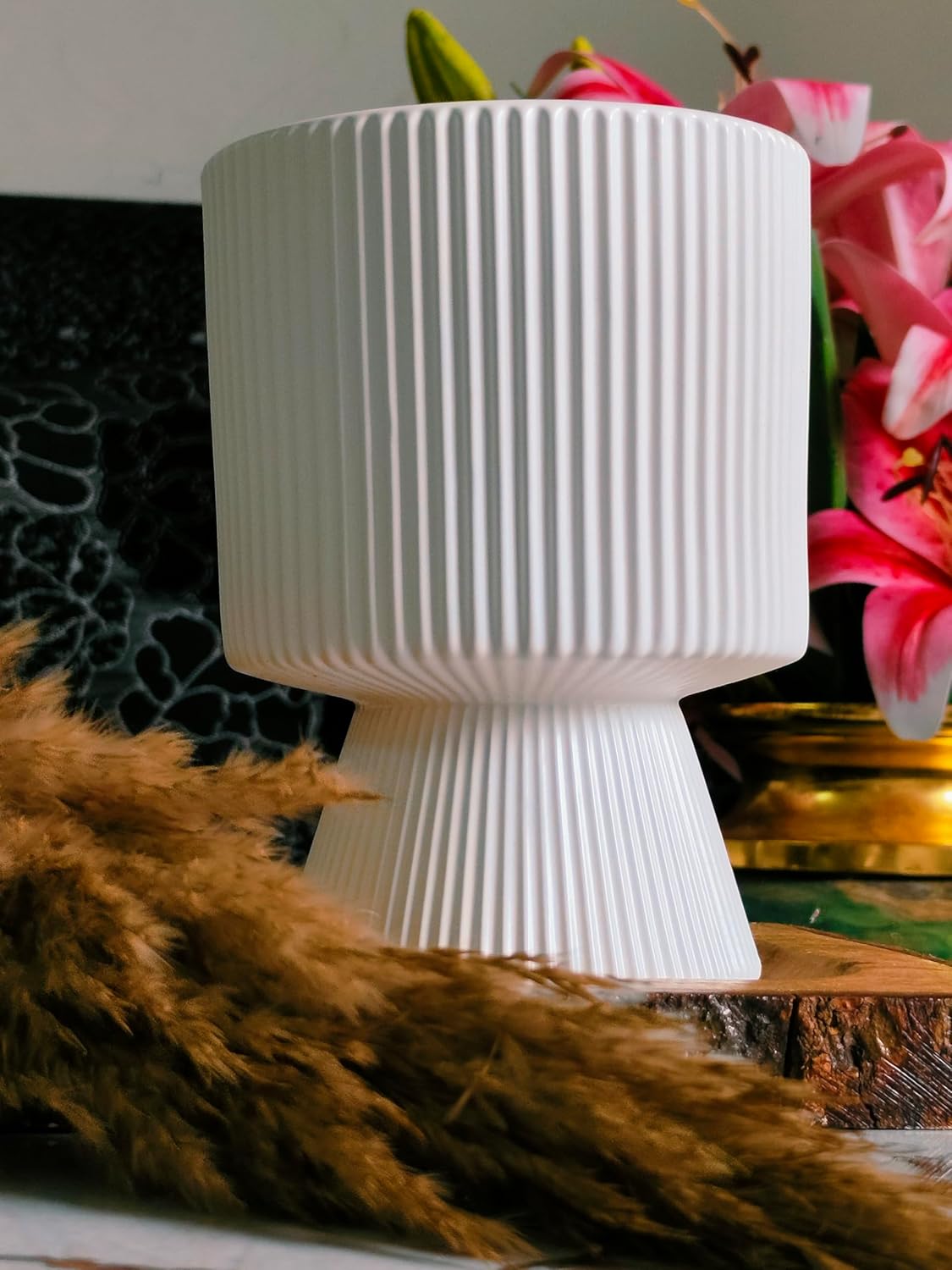 White textured vase on a surface with flowers in the background