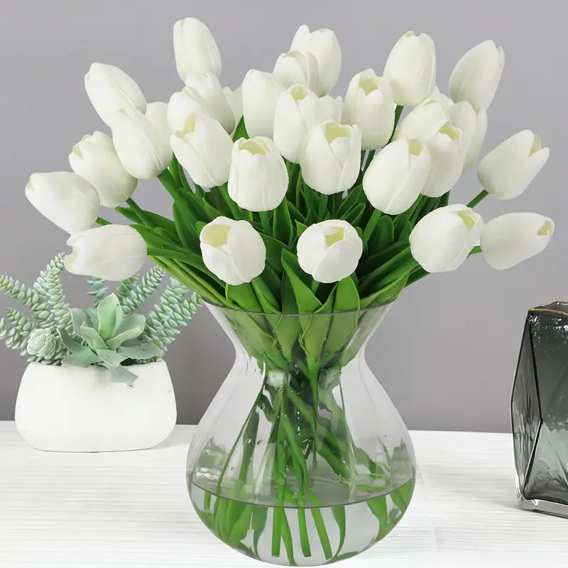 Bouquet of white tulips in a clear vase on a gray background