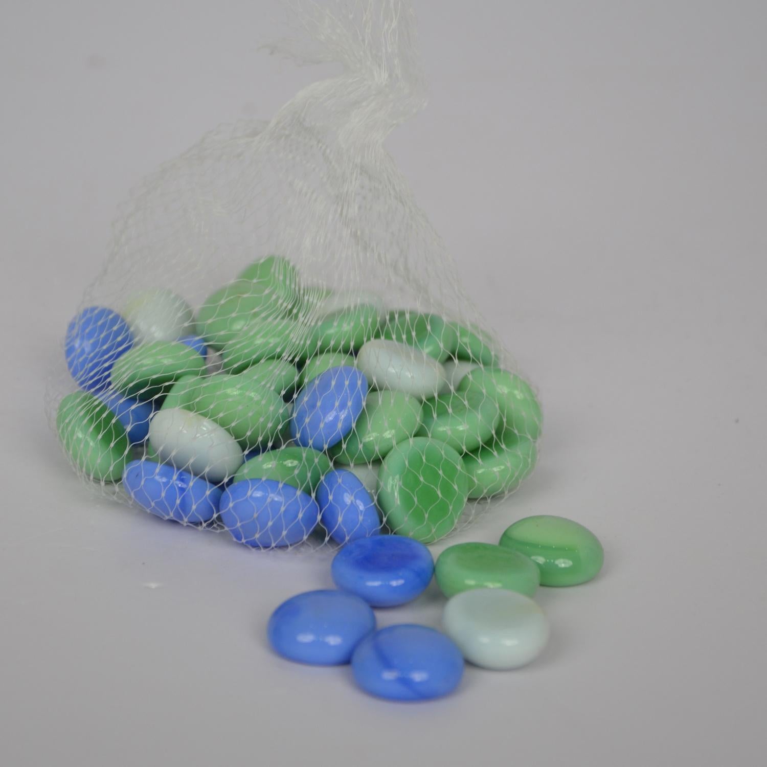 Bag of blue, green, and white marbles on a gray background
