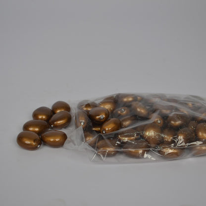 Gold pebbles spilling out of a clear plastic bag on a gray background