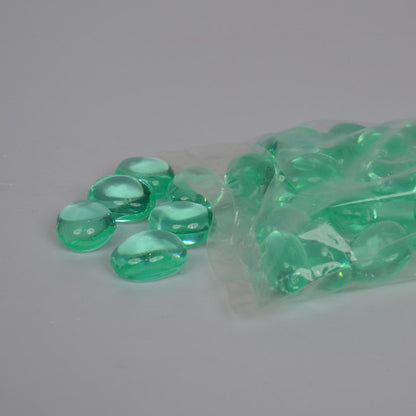 Green pebbles spilling out of a clear plastic bag on a gray background