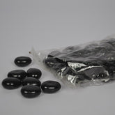 Black beans spilling out of a clear plastic bag on a gray background