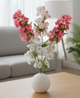 Floral arrangement in a white vase on a wooden coffee table with a blurred background