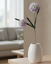 White vase with pink flowers on a wooden table in a living room setting