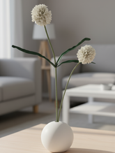 White vase with flowers on a wooden table in a living room setting