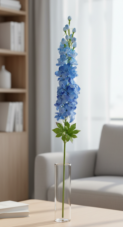 Blue flower arrangement in a clear vase on a wooden table with a neutral background