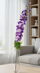 Purple flowers in a vase on a wooden coffee table with a neutral-colored sofa and bookshelf in the background.