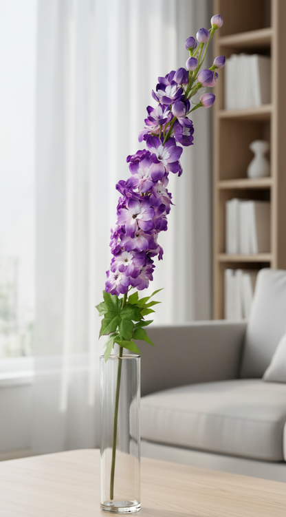 Purple flowers in a vase on a wooden coffee table with a neutral-colored sofa and bookshelf in the background.