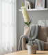 White flowers in a pot on a table with a cozy living room background