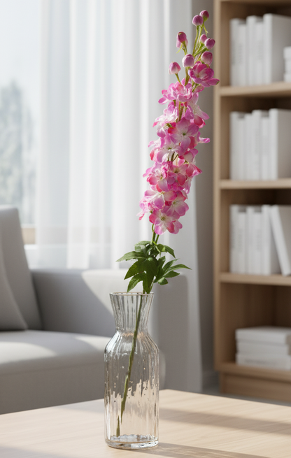 Clear vase with pink flowers on a wooden table in a living room setting.