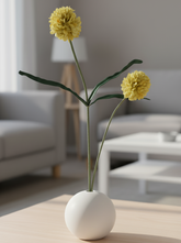 Yellow flowers in a white vase on a wooden coffee table in a living room.
