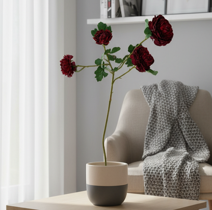 Modern living room with a coffee table, vase of red flowers, and gray sofa.