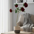 Modern living room with a coffee table, vase of red flowers, and gray sofa.