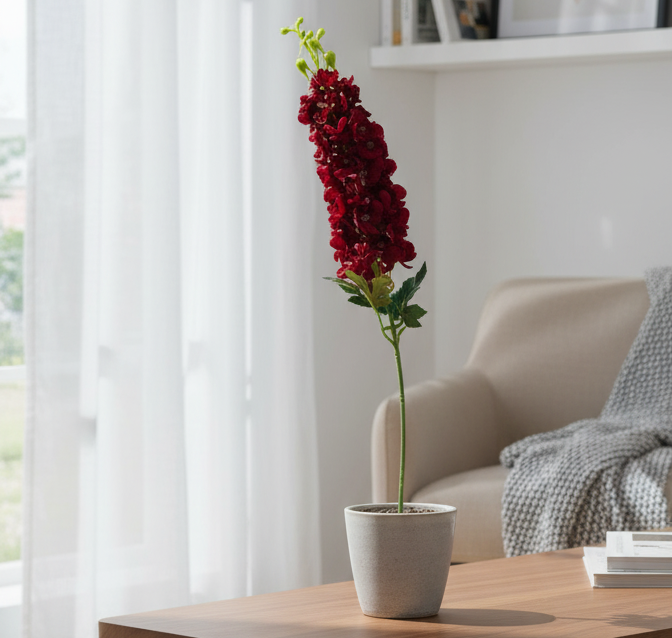 Red artificial flower in a pot on a wooden table with a blurred background
