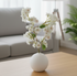 White vase with flowers on a wooden coffee table in a living room setting