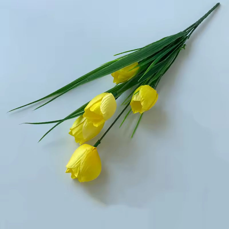 Bouquet of yellow tulips with green leaves on a light blue background