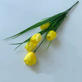Bouquet of yellow tulips with green leaves on a light blue background