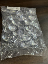 Clear plastic pebbles in a transparent bag on a wooden surface