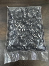 Clear plastic bag filled with black pebbles on a wooden surface